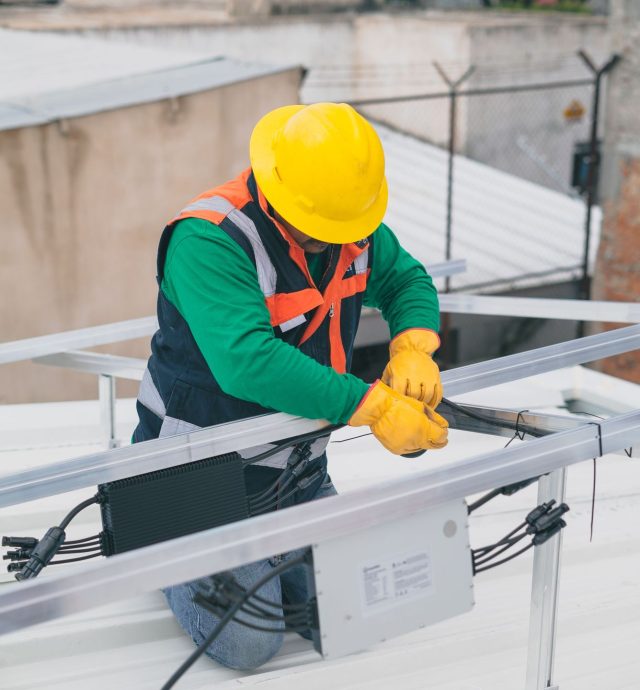 Técnico con casco instalando equipo eléctrico en una estructura metálica